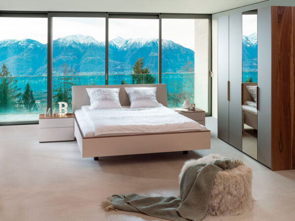 02: Bett in Lack grigio decklackiert, Kopfteil gepolstert in Decovin, Abdeckblätter Nachttische in Amerik. Wildnussbaum, Schrank mit Glasfronten in Spiegel Bronze und Bronze satiniert